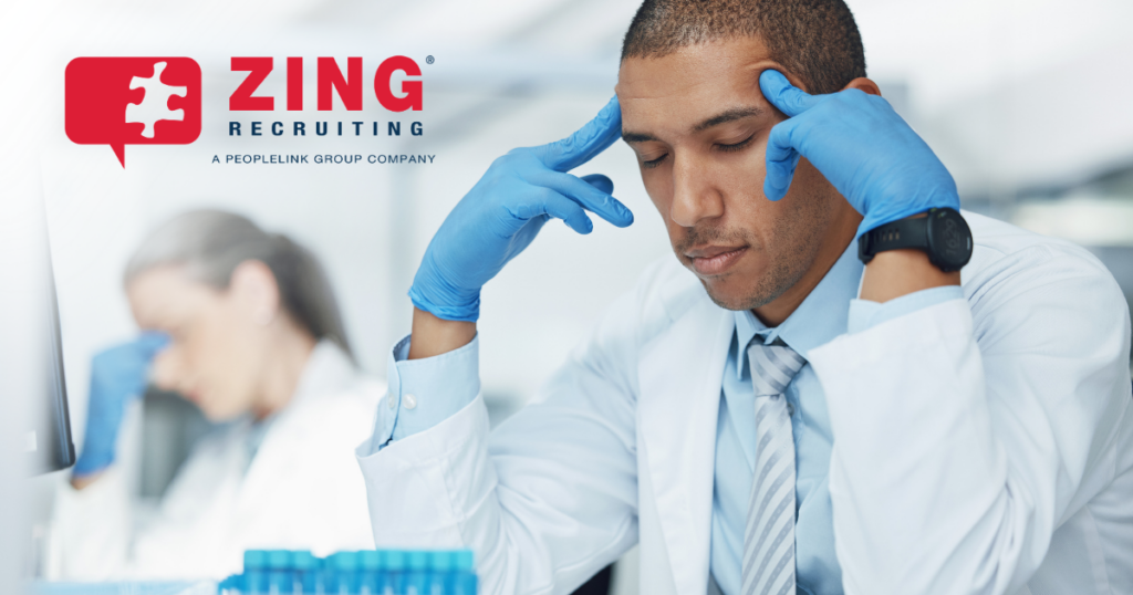 stressed out lab worker with gloved hands on temples